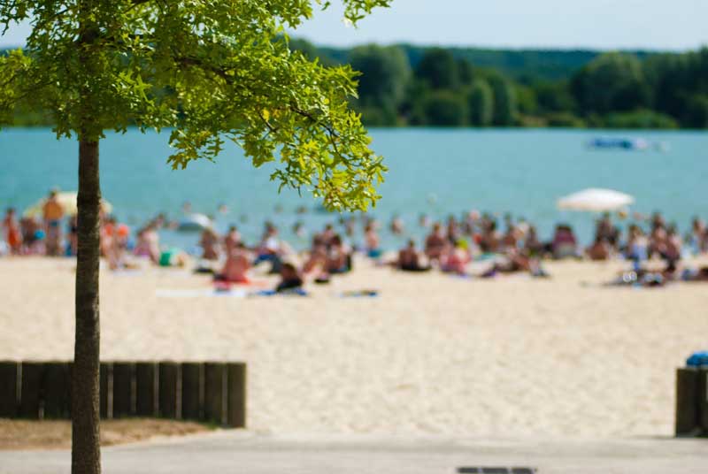 Personas sentadas en la arena al borde de un lago de agua clara en el Valle del Loir