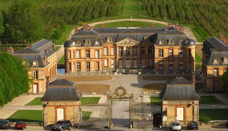 Monumenatal Chateau de Dampierre con tejado de pizarra rodeado de viñedos