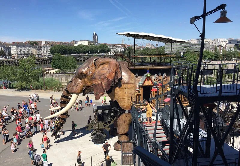 Elefante mecánico de madera gigante se mueve a través de una gran plaza pública en un parque temático en Nantes, Francia.