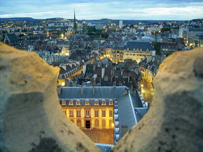 Vistas de Dijon al anochecer, edificios con tejados de pizarra y calles iluminadas, desde lo alto de una torre alta