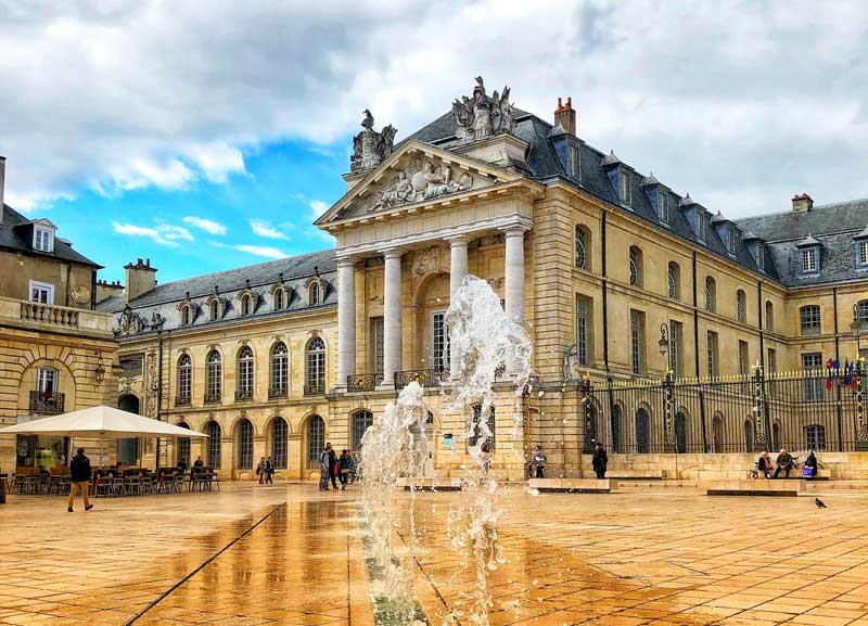 Fuentes en una gran plaza pavimentada frente al Palacio de los Duques en Dijon