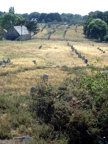 Largas filas de cientos de piedras de pie en un campo junto a una cabaña en Carnac, Bretaña
