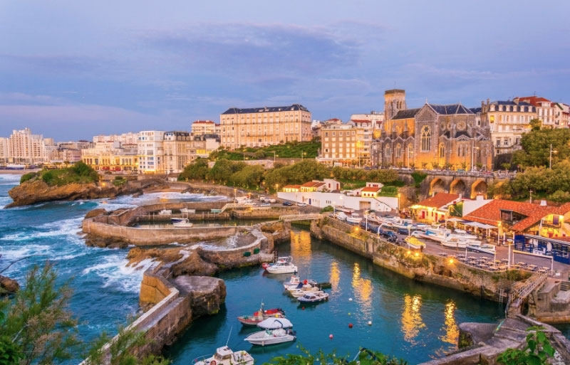 ª ciudad de Biarritz al anochecer, las luces de los edificios costeros se reflejan en el mar