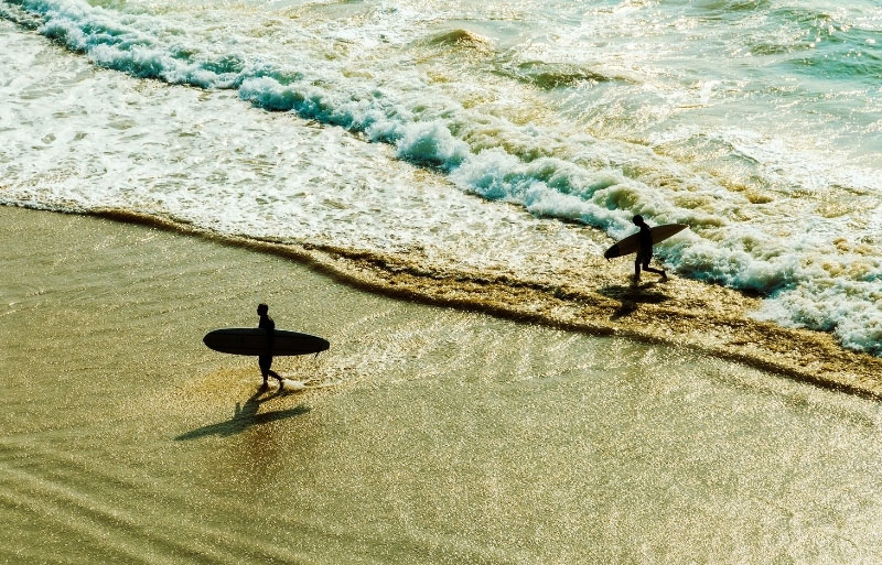 Dos surfistas con tablas en la arena dorada de Biarritz