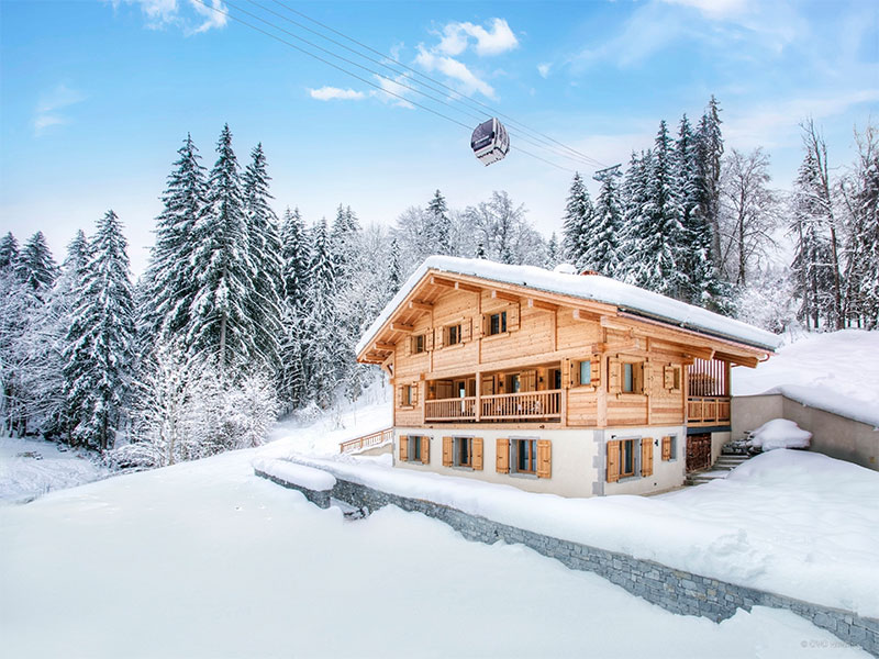 Magnífico chalet en los Alpes franceses cubiertos de nieve con un pequeño teleférico arriba