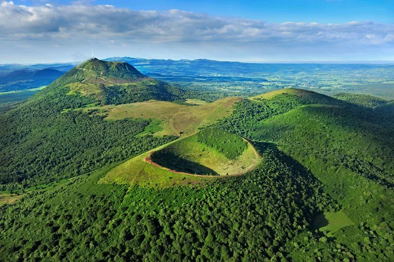 Volcanes inactivos cubiertos de arbustos, bosques y pastos en Auvernia