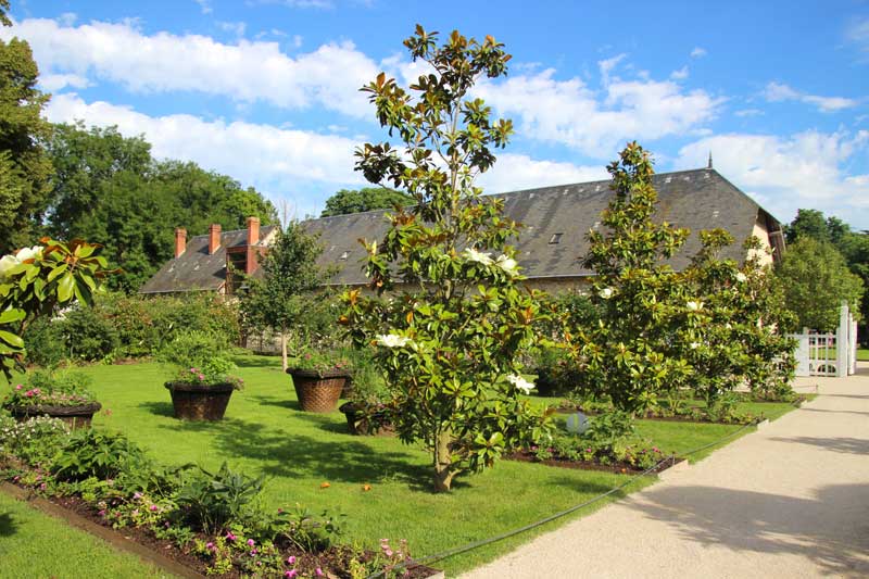 Jardín francés de estilo formal con bordes prolijos de flores y grandes macetas llenas