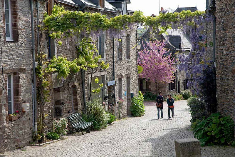 Dos mujeres caminando por una calle adoquinada, flores de primavera en flor, Morbihan, Bretaña