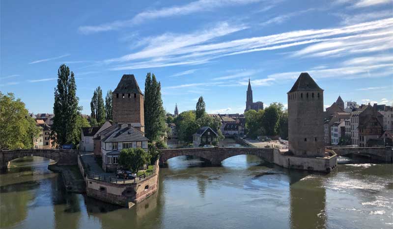 Una serie de puentes de piedra medievales con torres altas cruzan un río en Estrasburgo