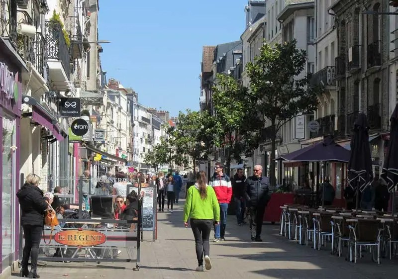 Calle en el casco antiguo de Dieppe, en Normandía, llena de edificios altos y muchas tiendas.