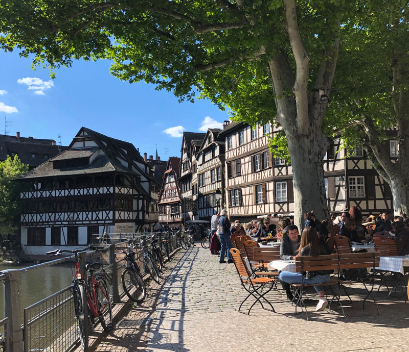 Bicicletas apoyadas contra una valla mientras la gente se sienta y disfruta de bebidas y aperitivos, Petite Ile, Estrasburgo