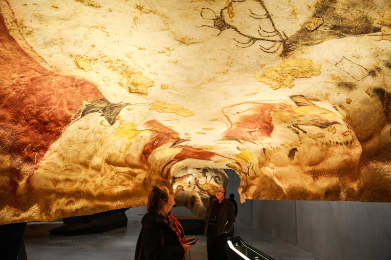 Mujer admirando el arte prehistórico en una cueva en Dordoña