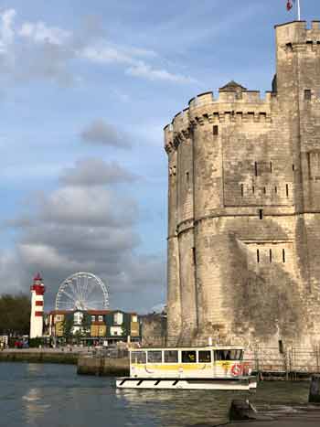 Un pequeño barco de recreo pasa ante la gran torre antigua de La Rochelle