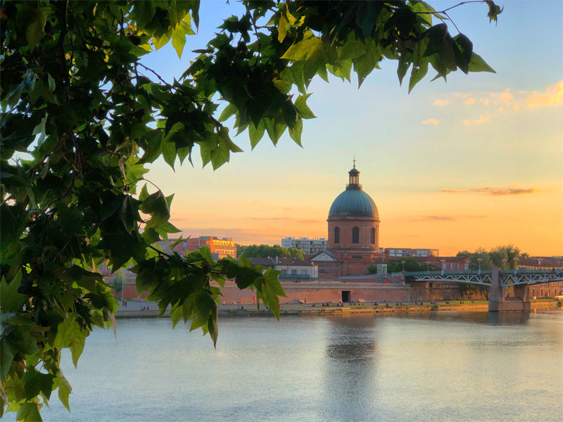 Vistas sobre el río Garona, Toulouse al atardecer, el sol iluminando edificios de ladrillo rojo