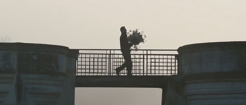 Hombre cruzando un puente levadizo en el Castillo de Chenonceau llevando un ramo de flores