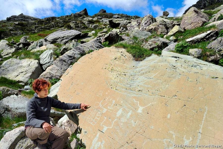 La arqueóloga Nicoletta Bianchi frente a la Roca del Fragmento, grabada con figuras corniformes y dagas