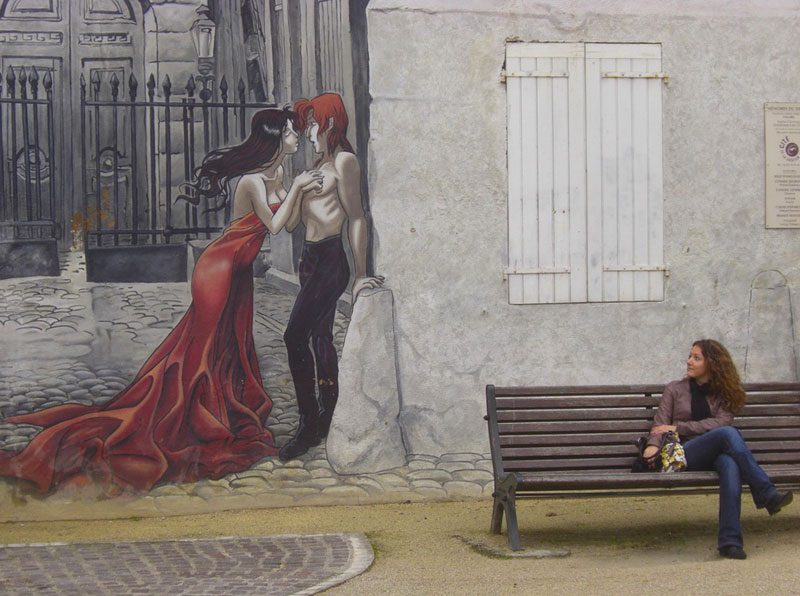 Una mujer sentada en un banco admirando un mural en Angouleme, en Charente, Francia