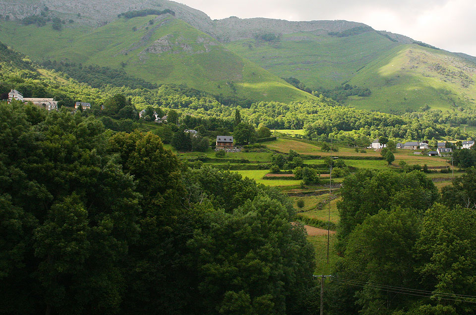 Altas colinas cubiertas de hierba y árboles rodean un pequeño pueblo en un valle