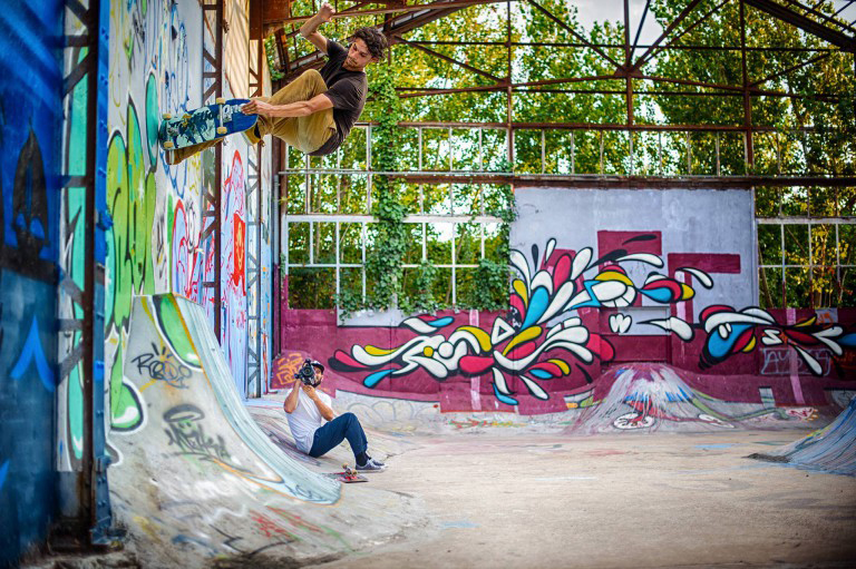 Hombre andando en patineta por una pared cubierta de grafiti.