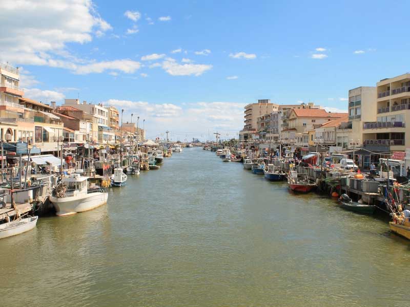 Un río desemboca en el mar en Palavas-les-Flots, en el sur de Francia, cafés bordean los muelles, barcos se balancean en el agua