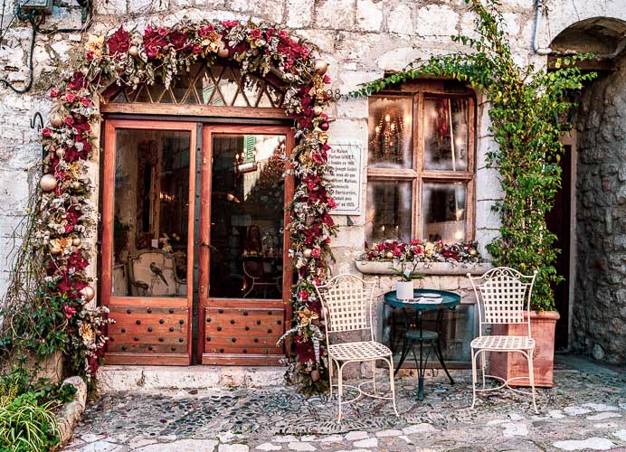 Café en terraza con rosas colgadas alrededor de la puerta en St Paul-de-Vence, Provenza