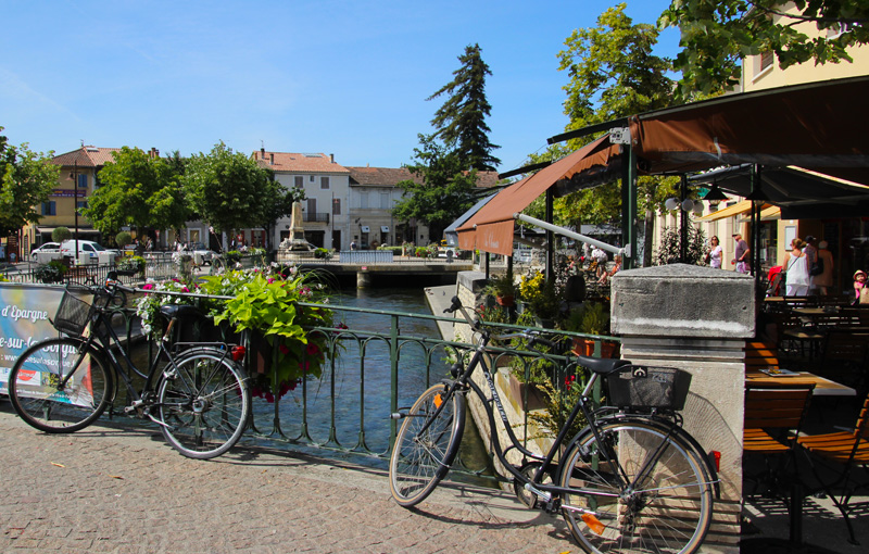 Bicicletas a lo largo de un río en un día soleado en la ciudad de Isle-sur-la-Sorgue, Provenza