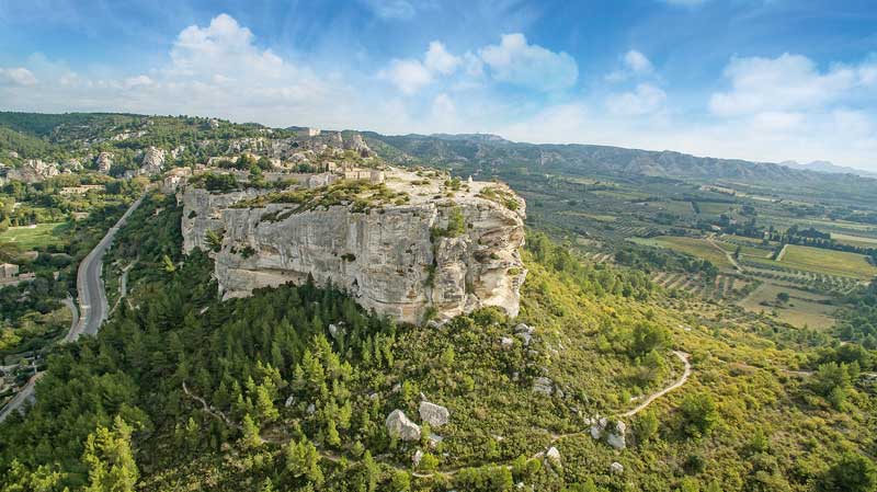 Vista de Les Alpilles, Provenza desde el cielo, un afloramiento rocoso en un mar de viñedos y bosques