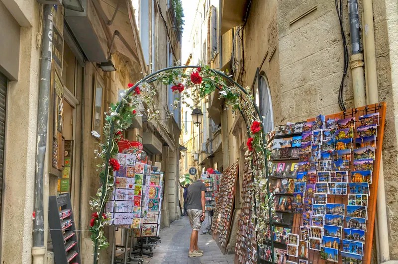 Calle adoquinada en el casco antiguo de Montpellier, repleta de tiendas y estantes de postales