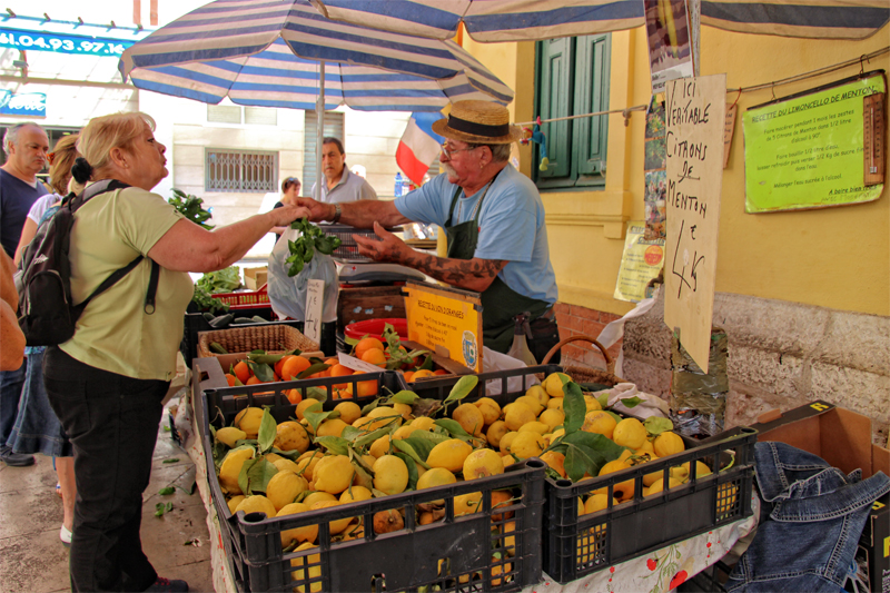 Una mujer compra limones frescos en un puesto en el mercado de Menton, sur de Francia.