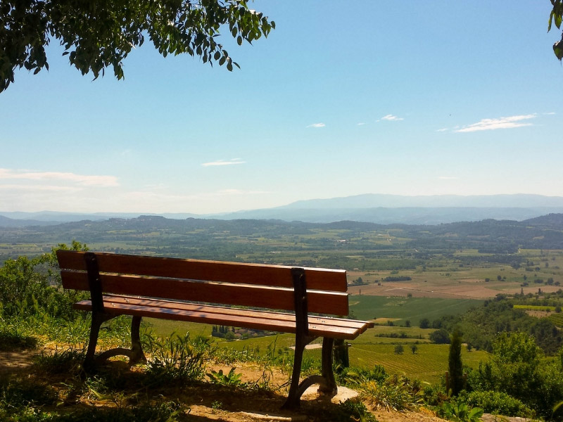 Un banco en la cima de una colina en Provenza con vistas a un hermoso paisaje