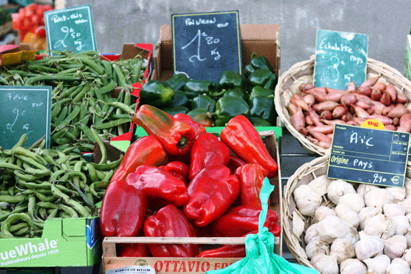 Pimientos rojos brillantes, judías verdes y ajo en un puesto en el mercado en Francia