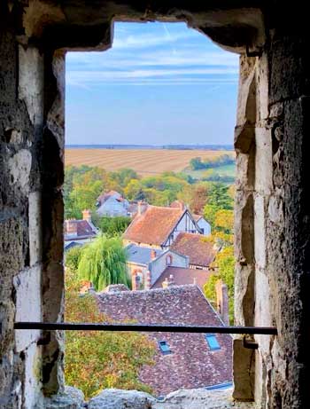 Vista a través de una antigua ventana de piedra sobre el campo y el pueblo de Provins