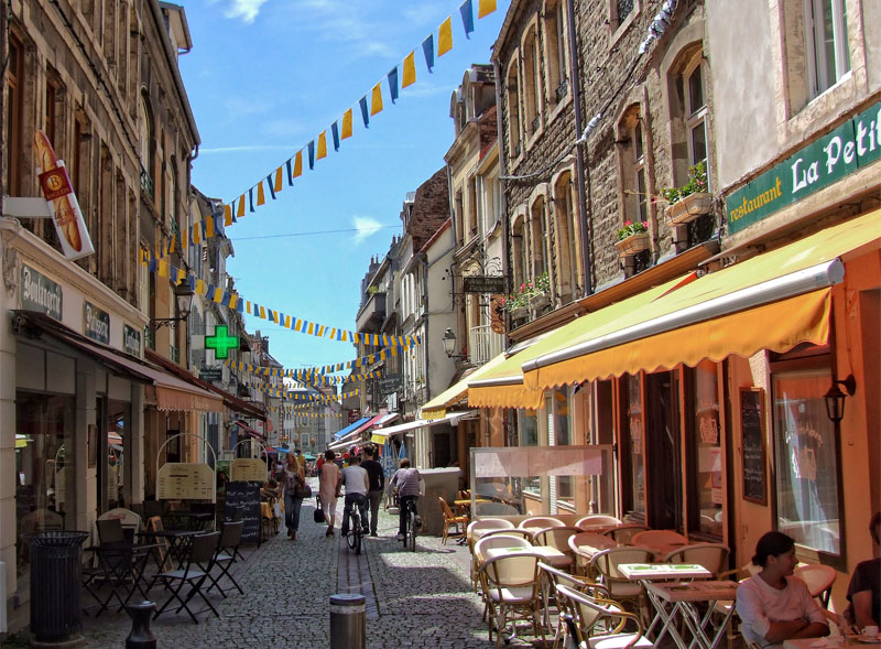 Calle adoquinada, adornada con banderines coloridos y llena de tiendas y bares extravagantes en Boulogne-sur-Mer