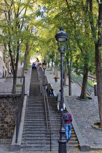 Escalones empinados en Montmartre, bordeados de árboles y farolas.