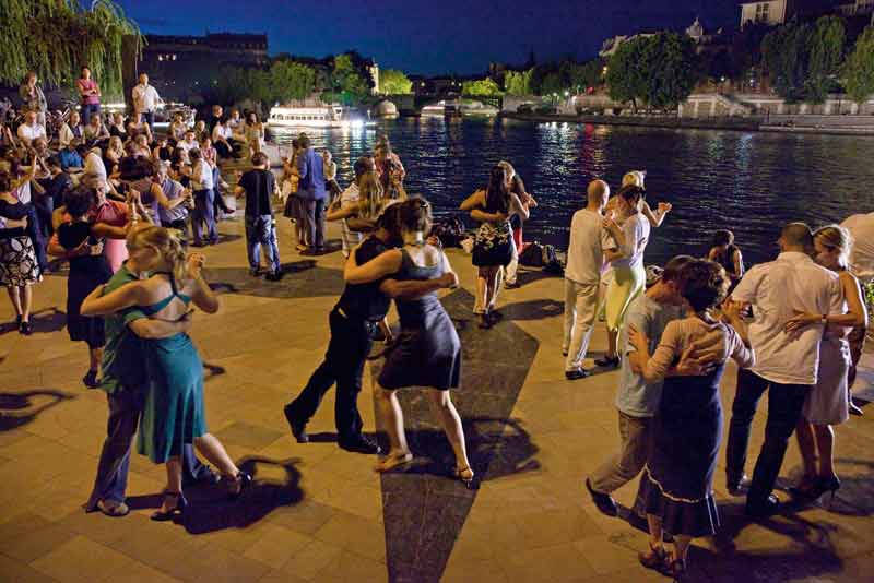 Bailarines de tango al aire libre junto al río Sena, París, por la noche