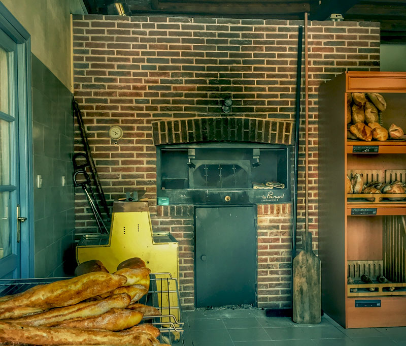 Horno de pan en una tienda en el norte de Francia, pan fresco sacado con una paleta de madera