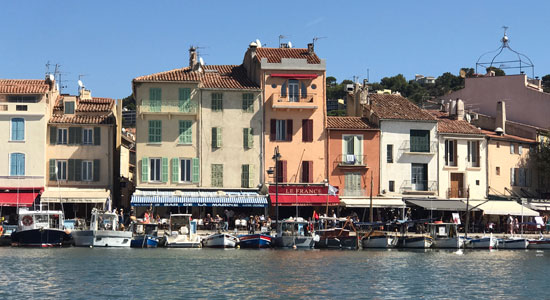 Cassis harbour lined with pastel coloured buildings and colourful shops